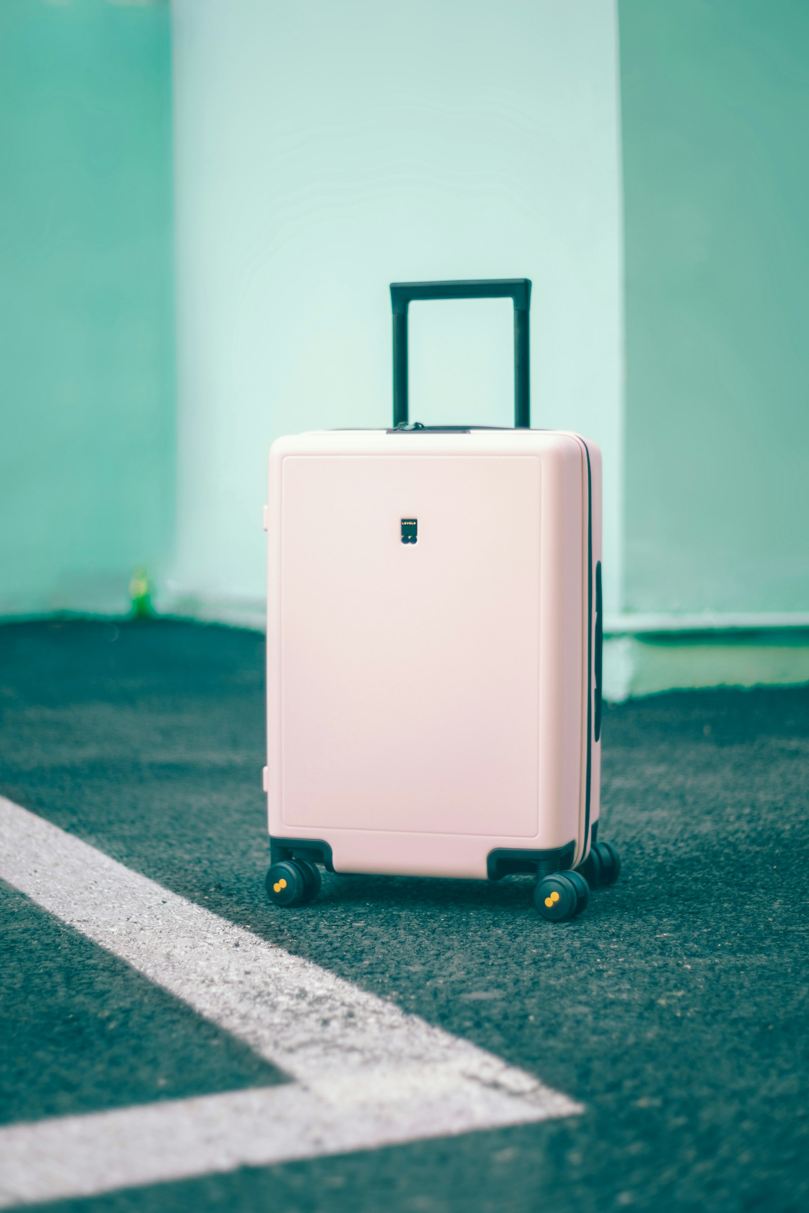Light pink hard-shell suitcase with four wheels and an extended handle
