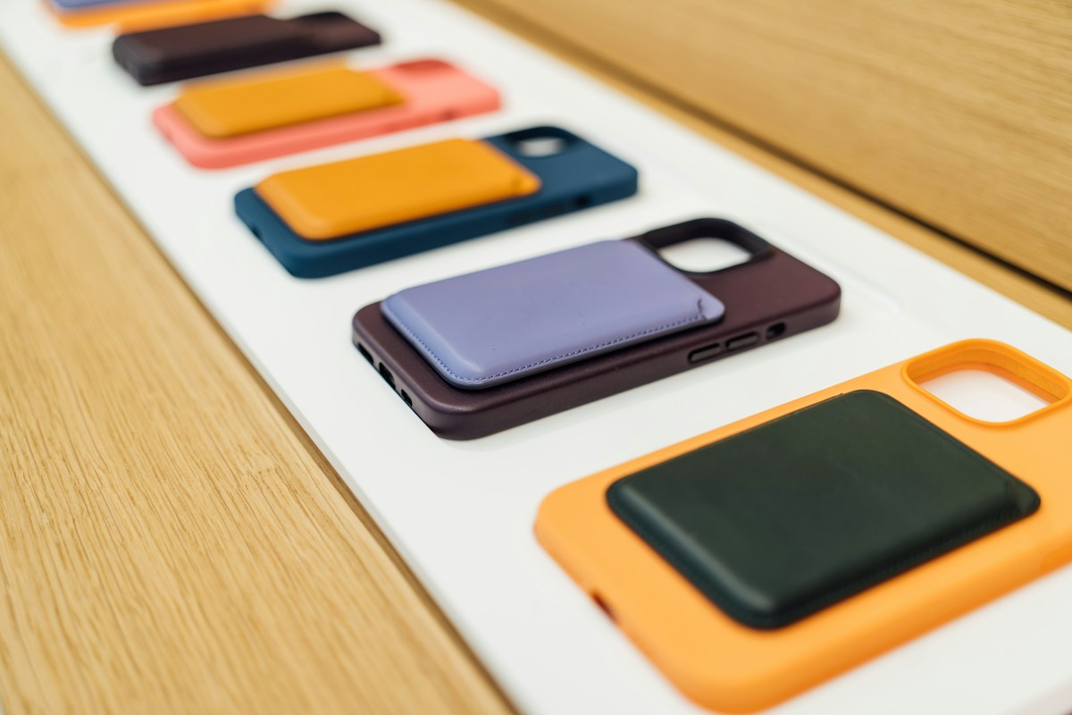 Colourful phone cases with card holders arranged on a white display beside a wooden counter