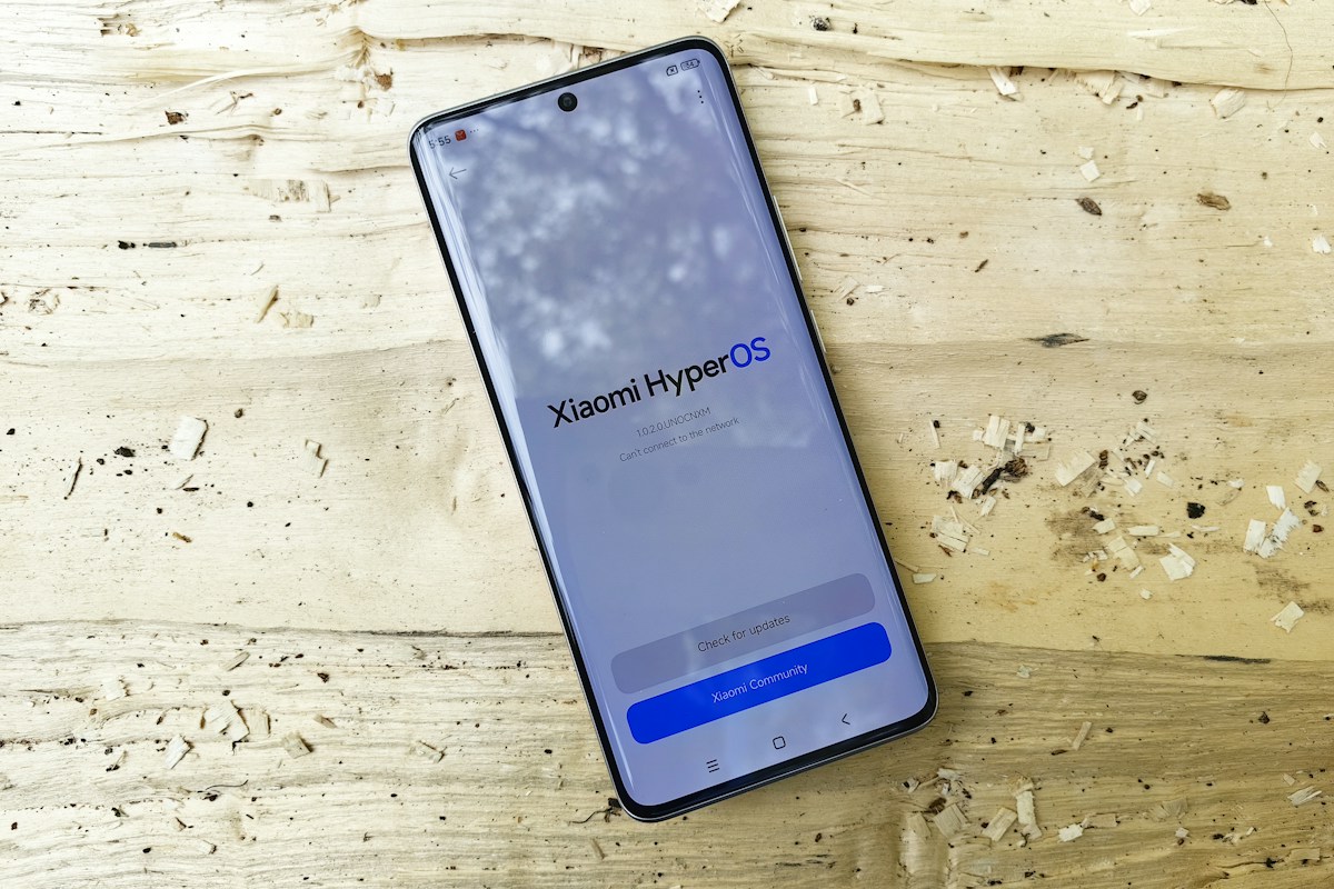 A smartphone showing its software information screen on a pale wooden surface