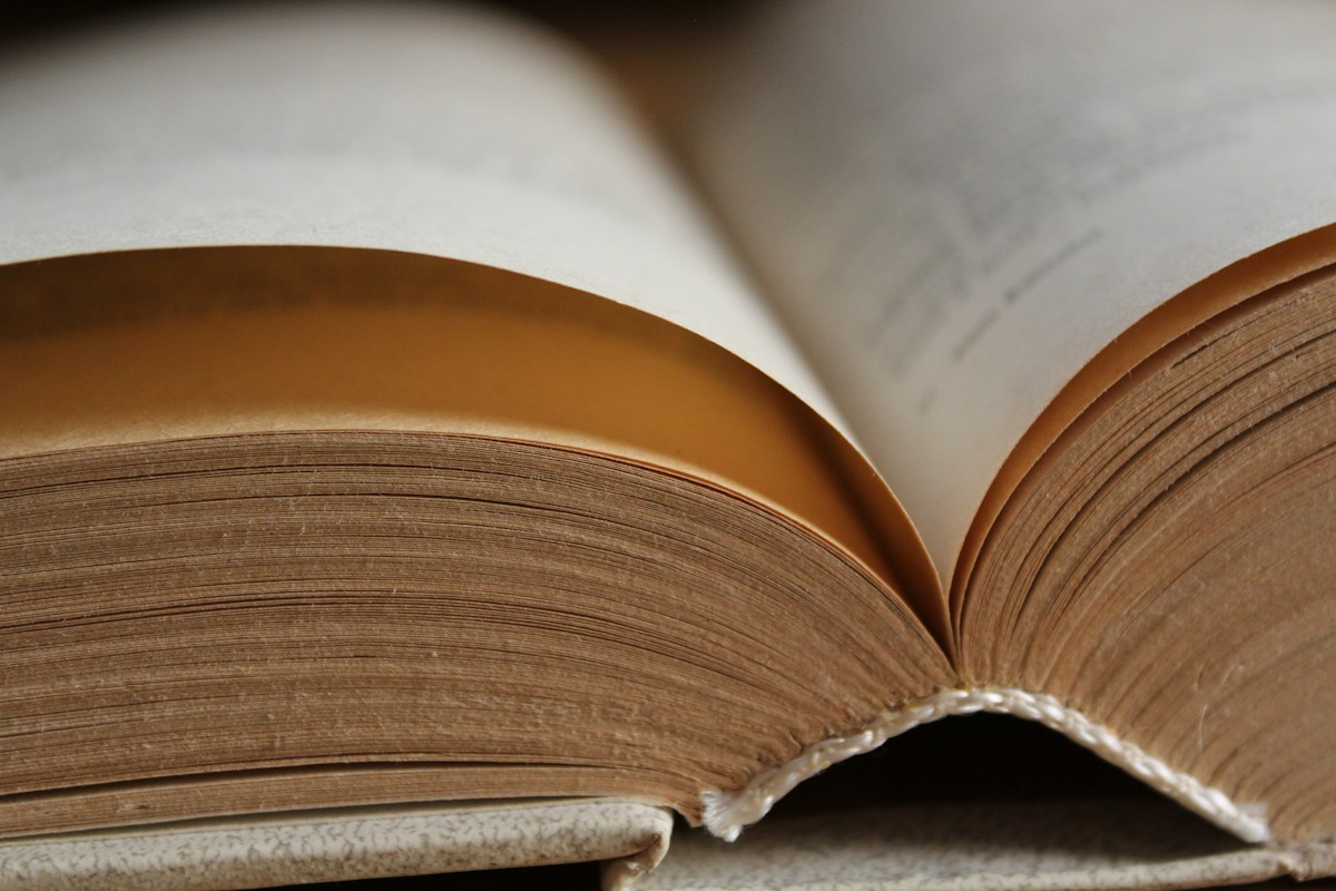 Close-up of the curved pages, spine and worn covers of an open hardback book
