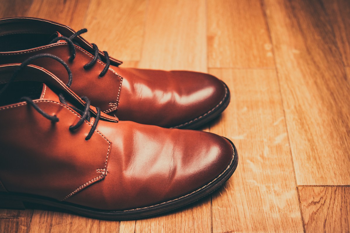Brown leather lace-up ankle boots on a wooden floor