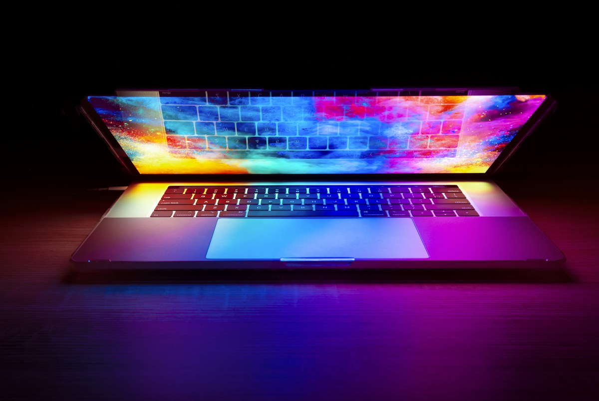 Open laptop with a colourful illuminated screen on a dark wooden desk